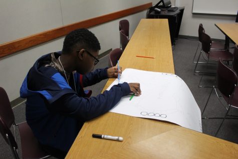 Student coloring a poster for a product design.
