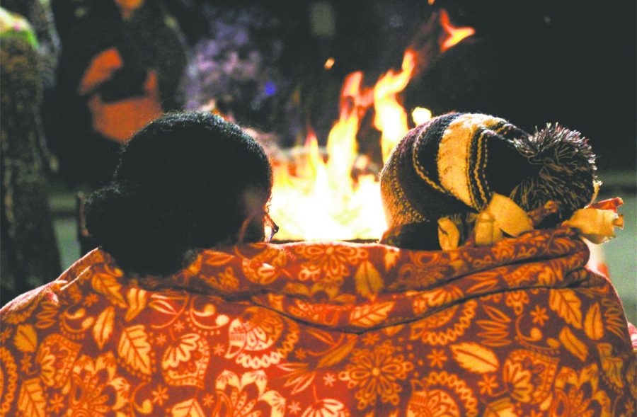 Sophomores+Tessa+Duncan+and+Katie+Shircliff+snuggle+up+by+the+fire+to+keep+warm+on+the+chilly+November+night.