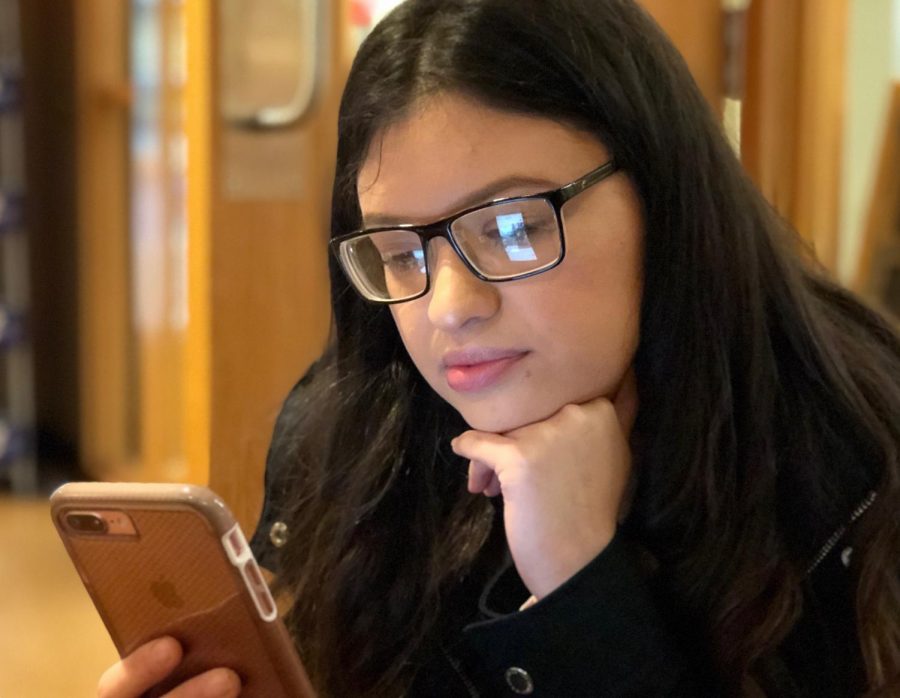 Angie+Munoz%2C+primary+education+sophomore%2C+uses+her+phone+during+leisure+time+at+University+Grounds+Coffee+Shop.+Photo+by+Meleena+Richardson.