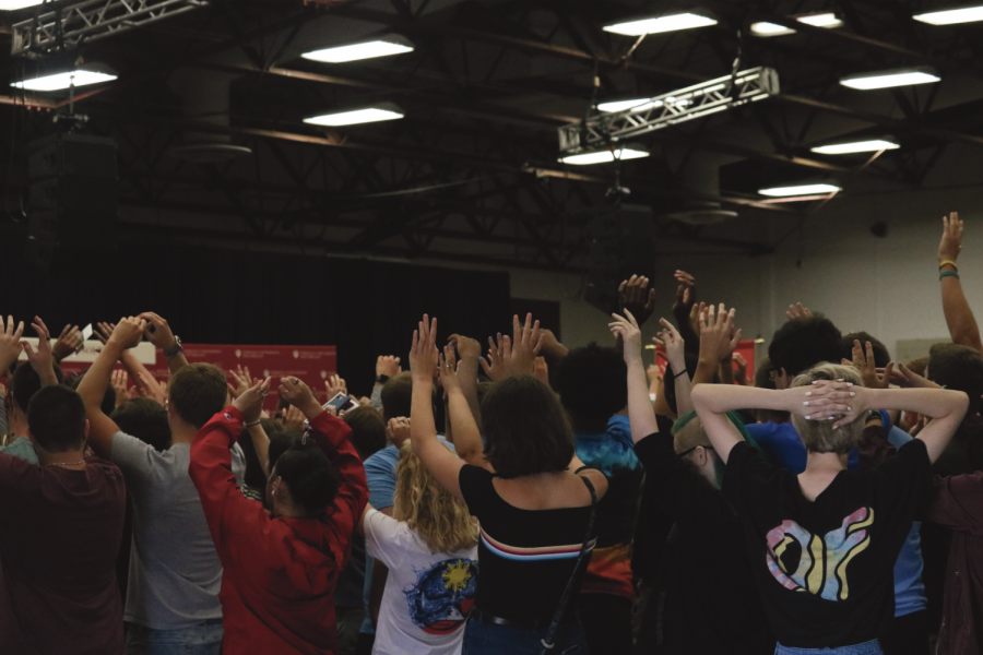 Students+raise+arms+in+the+air+as+they+do+the+wave+at+new+student+induction+day.