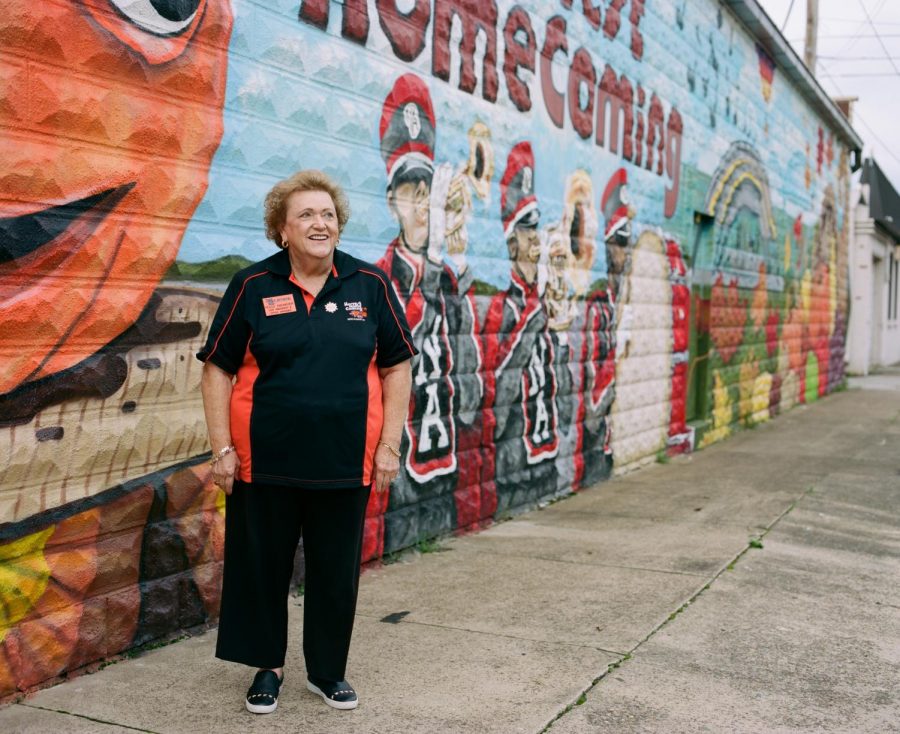 Polly+Niemeier+stands+in+front+of+a+mural+painted+on+the+Harvest+Homecoming+office+building.