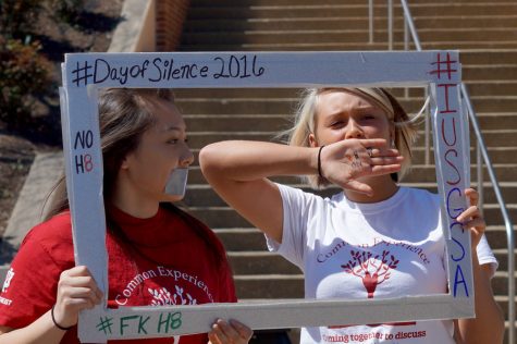 Thalia Tolentino, business freshman, and Taylour Corbett take pictures in their Day of Silence frame, covering their mouths to symbolize silence.