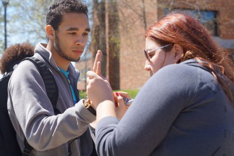 Bryan Simpson, psychology sophomore, lets Jordan Wingman, psychology sophomore, write NO H8 on his hand.