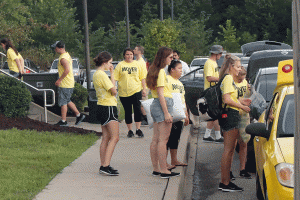 Volunteers help unload students belongings from their cars.