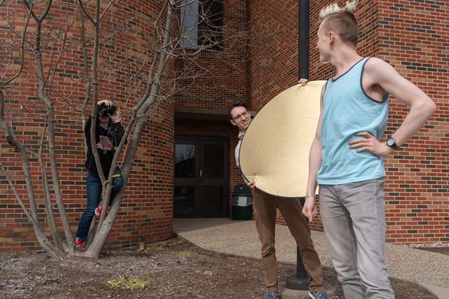 Junior Merlin Lee holds up a reflector while Junior Paris Brock takes a portrait of Junior Corgen Hobbs. Many projects in the Advanced photography class involve working in groups with one student acting as the model.