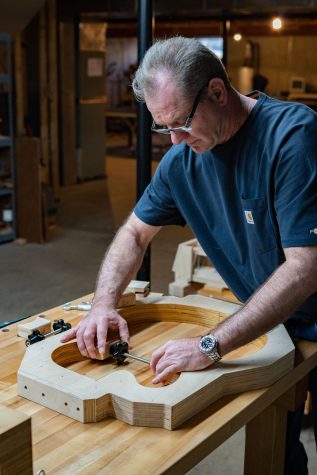 Mabe demonstrates how to set up a clamp in a mold. The clamp helps hold pieces of the guitar in place until the glue dries. 